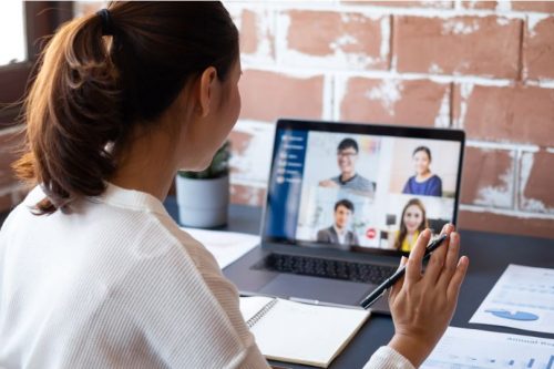 woman waving to 4 people on screen in a meeting